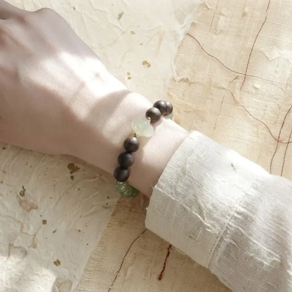 Elegant single-loop Jia Yang Wood beaded bracelet worn on a woman's wrist.